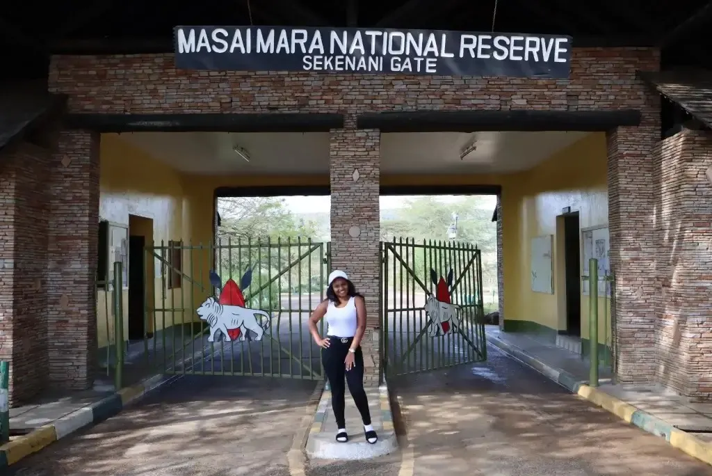 A traveler poses in front of the entrance gates at Sekenani Gate.