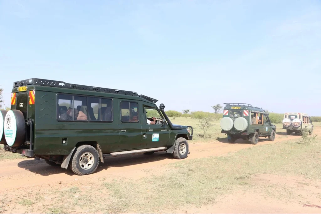 Private 4x4 safari vehicles driving on a savanna trail impacting masai mara safari cost.