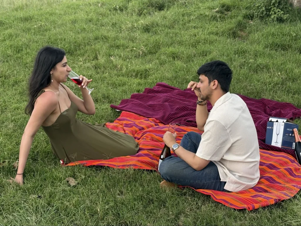 A couple drinking wine on a picnic blanket during a sundowner safari masai mara.