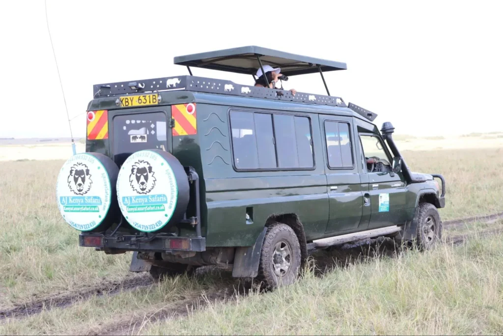 Tourists using binoculars from a 4x4 vehicle to explore the Masai Mara ecosystem.