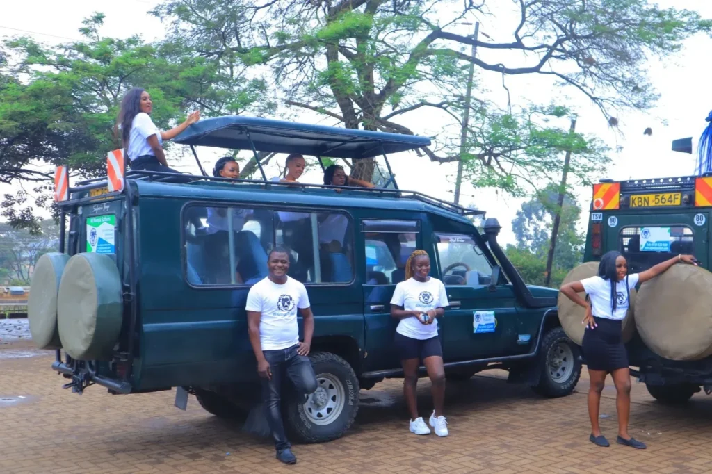 A group of international travelers posing on and around green 4x4 Land Cruisers on the best safari in kenya.