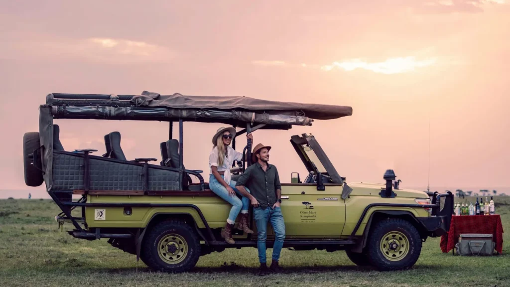 A couple enjoying a sunset sundowner next to an Olare Mara Kempinski safari vehicle.
