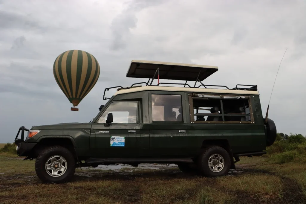 Safari vehicle and hot air balloon before a night game drive Masai Mara.