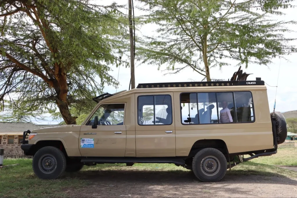 A beige 4x4 safari Land Cruiser parked under acacia trees during a trip from nairobi to masai mara by road.