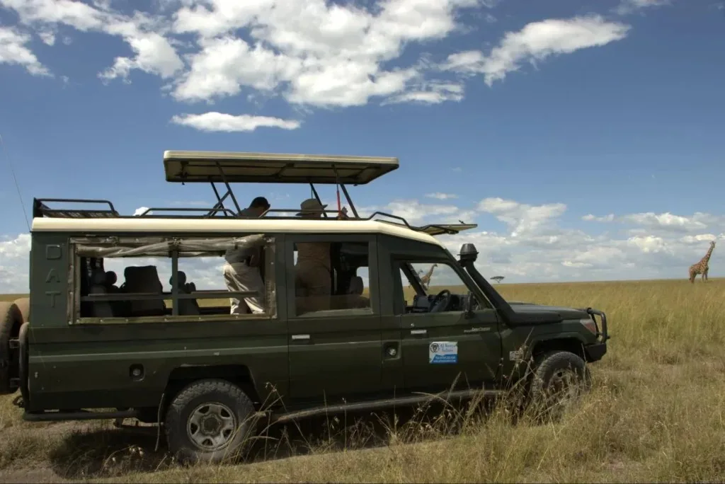 A green 4x4 safari vehicle parked in the grasslands showcasing Masai Mara size.