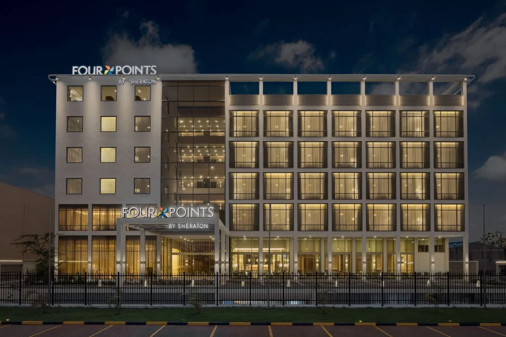 Illuminated modern luxury hotel exterior building facade at dusk near the airport.