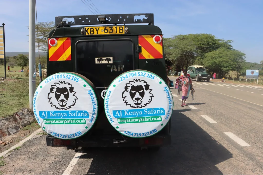 Rear view of a safari Land Cruiser with lion-logo wheel covers on a road.