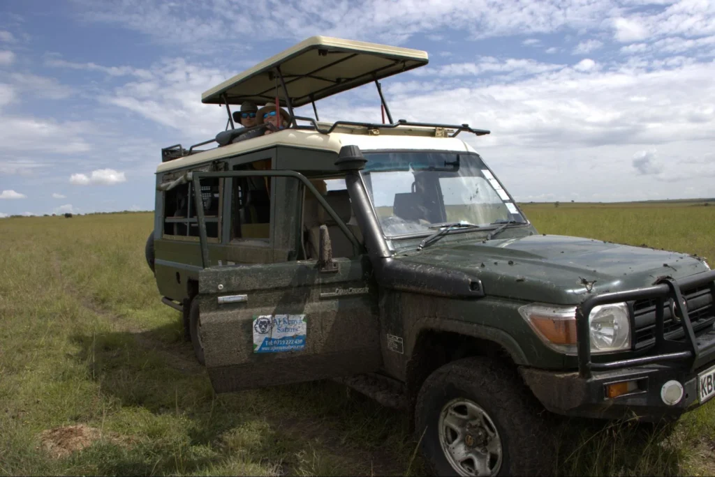 Tourists looking out from the pop-up roof of a safari vehicle in Kenya.