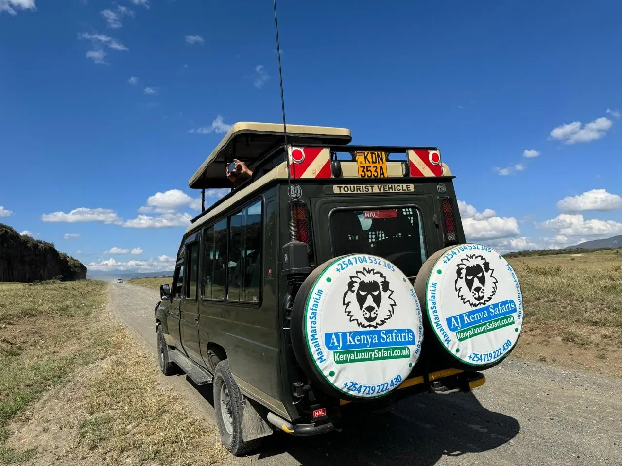 4x4 safari Land Cruiser with open roof driving on an open dirt road.