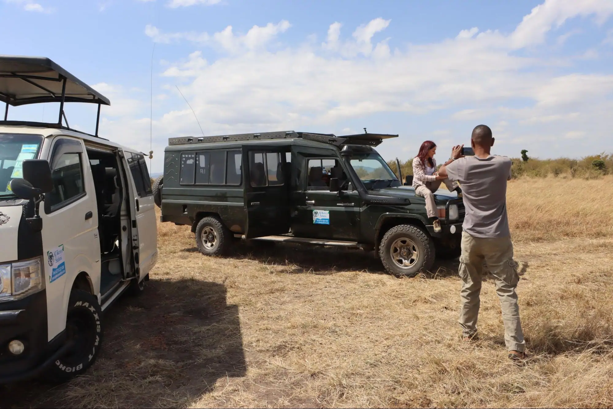 A man takes a photo of a tourist sitting on a safari vehicle.