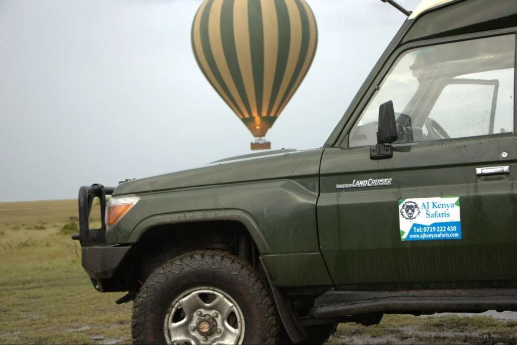 A 4x4 safari Land Cruiser with a hot air balloon floating in the background.