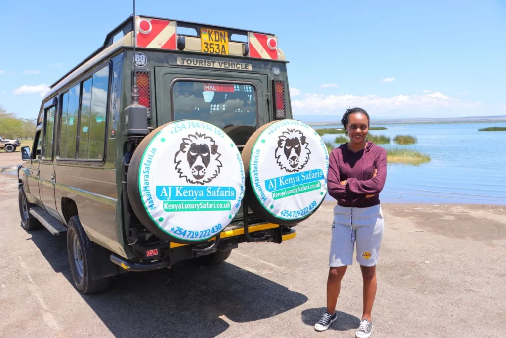 A professional travel consultant standing beside a custom safari Land Cruiser near a scenic lake.