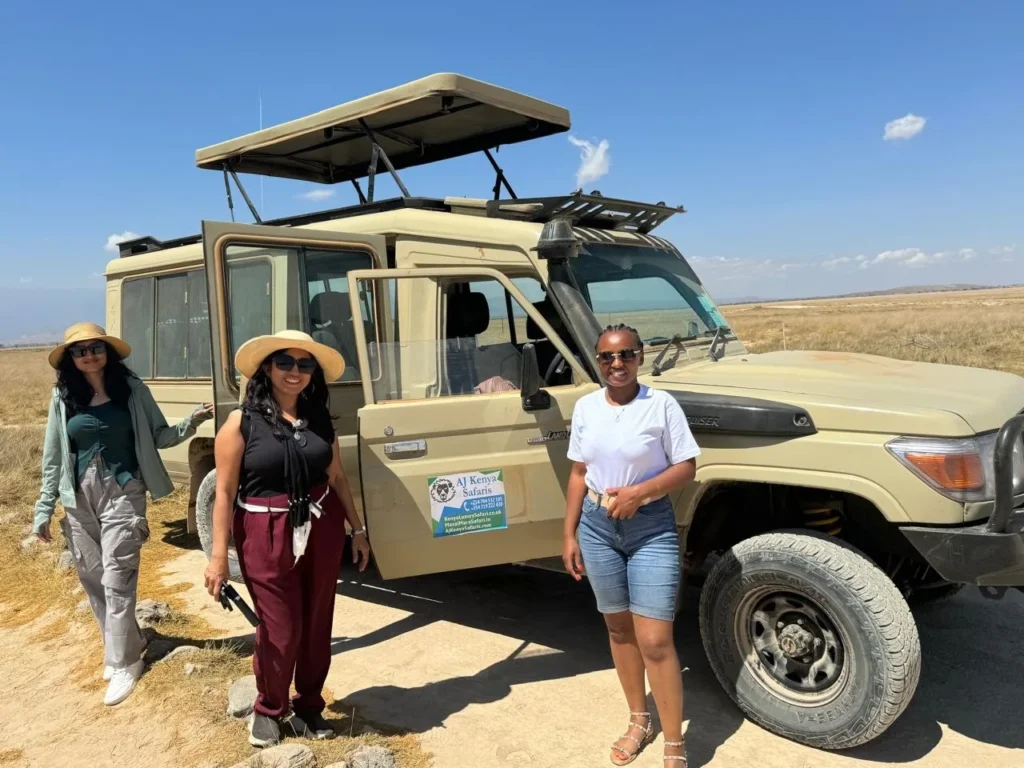 Happy travelers standing by a custom safari vehicle with an open pop-up roof.