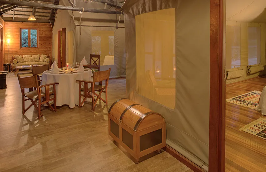 Family tent interior at Sarova Mara featuring a dining table, wood floors, and trunk.