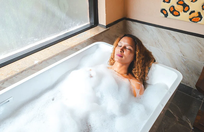 A woman relaxes in a bubble-filled bathtub inside a Sarova Mara Club Tent.