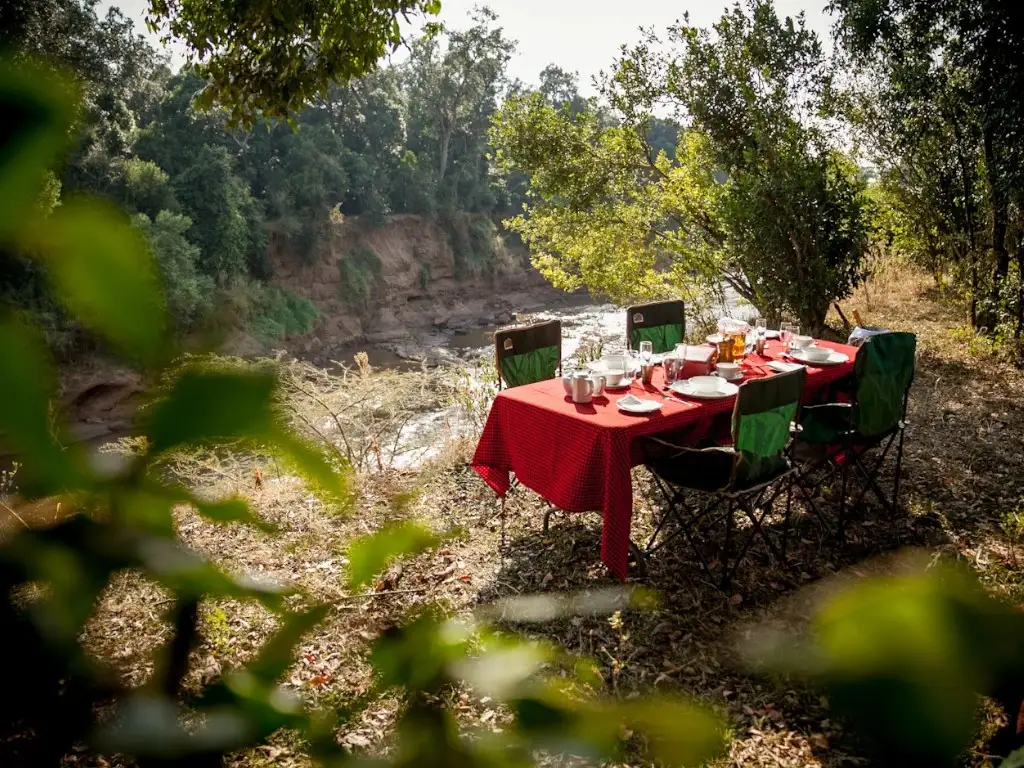 A dining table set for a bush breakfast overlooking the Mara River.