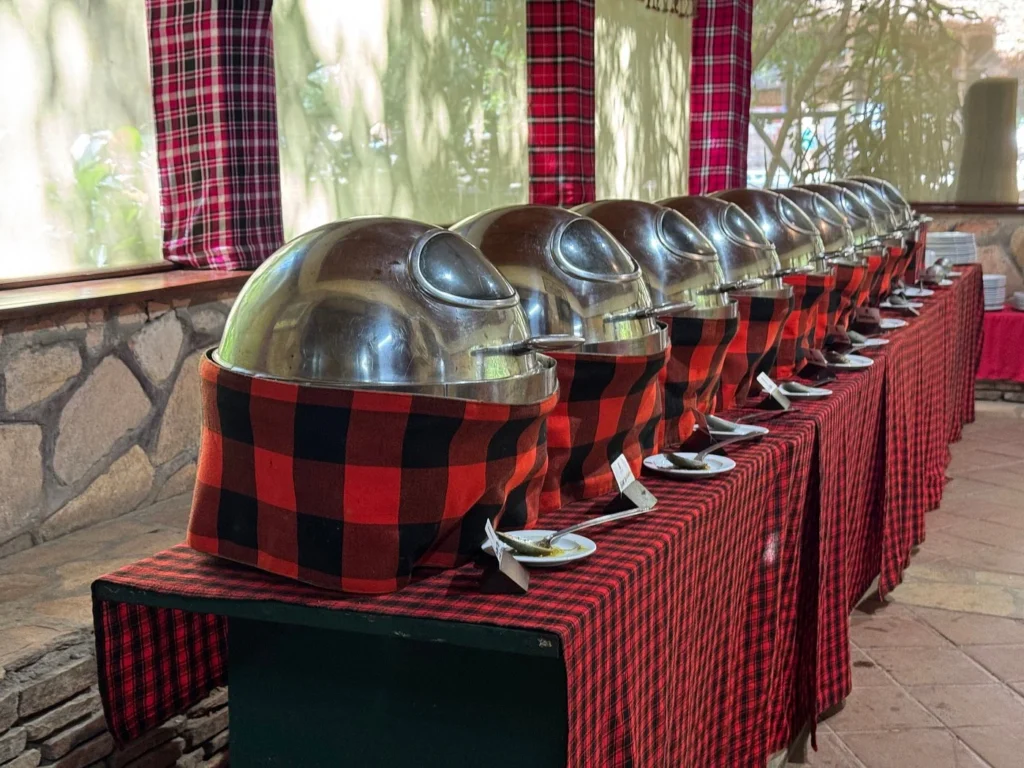 Silver buffet chafing dishes wrapped in red and black Maasai shuka fabric at camp.