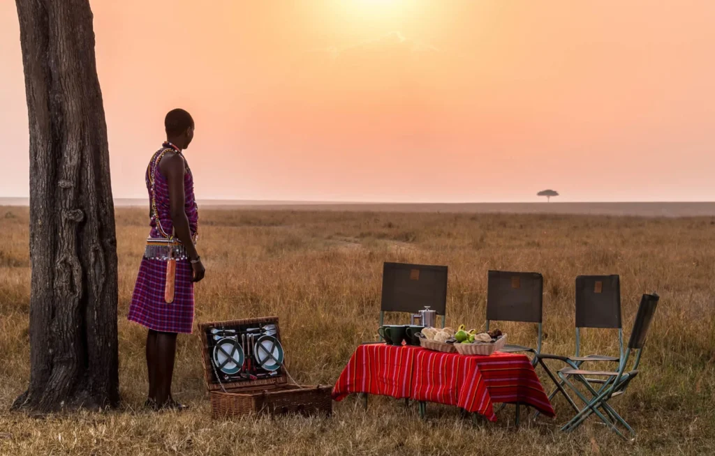 Entim Mara Camp bush breakfast setup on the savannah plains with a Maasai warrior.