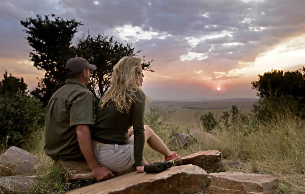A couple enjoys a sunset over the savannah from Sundowner Hill at Entim Mara Camp.