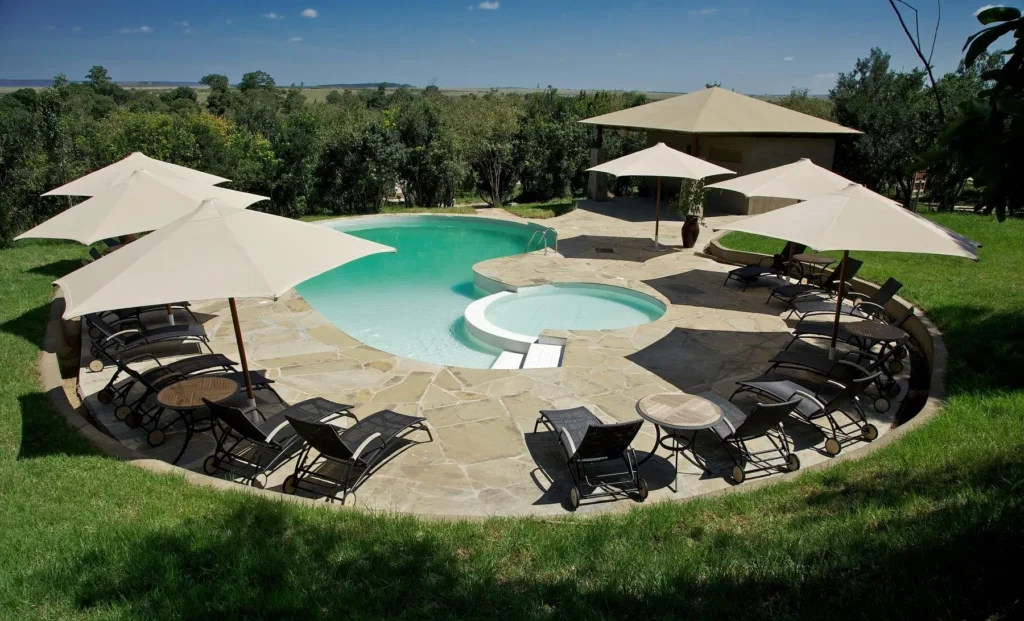 The outdoor swimming pool and lounge chairs at Ashnil Mara Camp surrounded by trees.