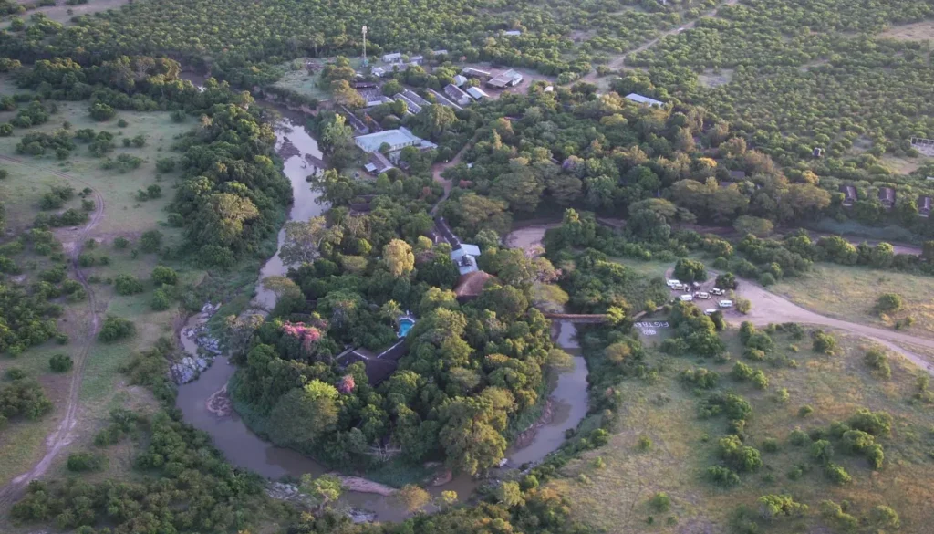 Aerial view of Fig Tree Camp surrounded by trees in a bend of the Talek River. Title: Aerial View of Fig Tree Camp